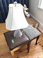 Crystal lamp placed on top of two benches, showing the lamp's fabric shade and crystal base along with the two benches, one with leopard print fabric and one with brown vinyl.
