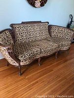 View of entire antique three-seater settee showing carved wood frame and floral upholstery.