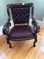 Front view of antique leather chair showing tufted back and claw-front feet