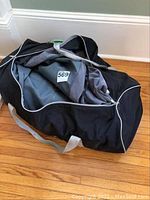 Black and gray storage bag partially open showing the mattress inside