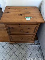 View of the pine side table showing two drawers and natural wood grain with knots, placed on carpet near couch.
