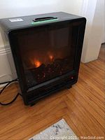 Front view of black portable electric fireplace showing flame effect inside the unit.