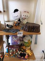 Shelf with stuffed crocheted cat couple, carved loon bird, stained glass black cat plaque, Lion King figurines and lamp base, Garfield Pez dispenser, and other small figurines and collectibles.