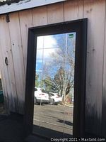 Full view of the full length beveled mirror showing the frame and division into panes reflecting outdoor scenery.