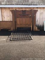 Full view of oak headboard with carved decorative center, oak footboard, and metal springs laid on pavement.