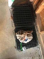 Stack of 56 black metal wire grid panels bundled with plastic cap connectors, showing overall quantity and condition.