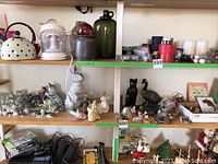 Wide shelf display showing multiple ceramic and animal figurines including cats, a rabbit, and goose, with various household items visible.