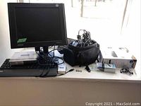Samsung 17 inch monitor, IBM keyboard, Sylvania HDMI DVD player and cords, Sony video camera in soft case, assorted cords and accessories shown on a white surface.