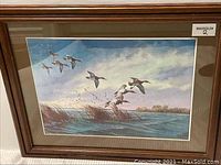 Front view of framed David Maas metallic etching print featuring flying ducks over water and reeds.