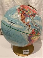 Photo of globe showing North and Central America, part of the gold-colored metal stand, and geographic details with colorful country demarcations.
