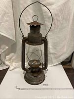 Full view of the GSW Beacon kerosene lantern standing showing metal frame, handle, glass chimney and base.