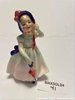 Front view of the Royal Doulton Babie figurine showing the detailed face, bonnet, dress, and umbrella.