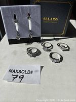 Photo of 4 silver-tone rings with clear crystals and 3 pairs of matching earrings displayed with SLAISS Swarovski box