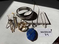 Five pieces of assorted jewelry including two pairs of earrings, two bracelets, and one necklace with a distinctive blue stone pendant.