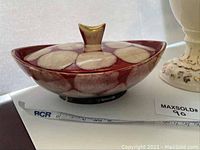 Photo of covered dish with maroon and cream glaze, handle visible with a chip