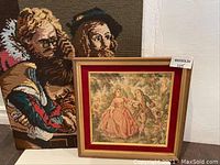 Two fabric art pieces displayed side by side: a framed romantic couple tapestry and an upholstery style textile of two men.