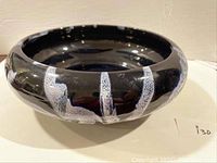 Photo of black Blue Mountain Pottery bowl showing exterior with white textured vertical stripes.