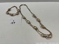 Full view of sterling silver necklace and bracelet set showing linked oval beads and chain design