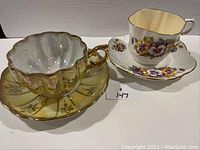 Photo showing both tea cups and saucers side by side, highlighting designs and condition