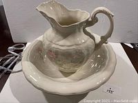 Full view of the ceramic jug resting inside the basin, showing the floral decoration and overall shape of the set.