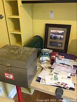 Metal mailbox on table near first day covers and framed stamp display