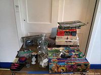 Overall view of lot showing stacked model kits including Warhammer, Studio Ghibli Laputa, paper airplane kit, microscope box, and various small items scattered on the table