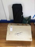 Photo of all three chess sets including box, black roll-up carrying case, and green bag container.