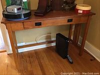 Front view of the wooden desk with hideaway writing area. Some items placed on top and below the desk for scale and context.
