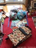 Photo showing two large bags of yarn, smaller bag of wood pieces, tin of buttons, craft books, and the rolling bag with butterfly design.