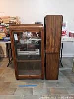 Wood stereo cabinet with glass doors shown from front and side, containing stereo components.