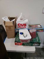 Photo of Christmas decorations on table showing boxes, a CVS bag with candy cane rope lights containers, and boxed holiday sets.