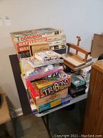 Photo of stacked board games and wooden bowling ball holder on table