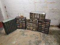 Five different metal storage cabinets with multiple small drawers filled with various hardware items