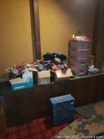 Wide shot showing multiple boxes containing assorted bicycle parts and accessories on a wooden counter with a red carpet floor below.