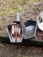 Orange Craftsman chainsaw inside black protective metal carrying case showing overall item condition with dirt and grime.