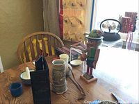 Photo of assorted collectibles including nutcracker, stein, abacuses, shelves, teapot on wooden table near window