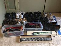 Multiple men's shoes including Sketchers, New Balance, Rockport, Crocs, and Doc Martens, two plastic bins with ties and accessories, tie rack and fish shaped novelty tie.