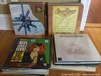 Three stacks of vinyl records showing album cover details: Willie Nelson's 'Pretty Paper' wrapped in a gift design, Nina Hagen Band with colorful artist illustration, and Bob Seger's 'The Distance' featuring a sunset profile.