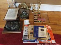 Overview of all lot contents on floor: plaques, frames, clock, trophies, display case and ephemera.