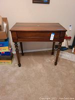 Full view of the wooden desk showing hinged top and turned legs