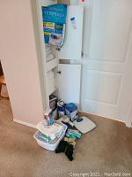 Photo of linen closet showing mattress pad, folded sheets, towels, personal care items, and medical devices on floor.