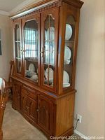 Full view of the china cabinet and buffet showing three glass-paneled doors and bottom storage cabinet with brass pulls.