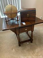 All items displayed on drop-leaf side table: table, globe, wooden chest.