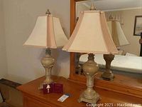 Pair of table lamps on wooden dresser with mirror, showing full lamp shape, base, and fabric shades