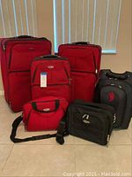 Full view of the luggage set including 3 red suitcases, a red small bag, black rolling bag, and black backpack.