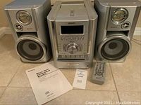 Full view of Sony stereo system with two speakers, remote control, and manuals on floor.