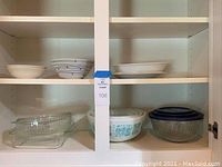Overall view of shelf with clear glass bakeware, milk glass turquoise patterned bowls, and ceramic plate and bowls.
