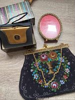 Two vintage ladies handbags, one beaded with floral design and one black and gold Elgin American purse with box.