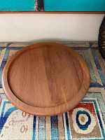 Top view showing circular teak tray with smooth finish and raised edge.