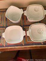 Overhead view of all four Corning Ware dishes on table showing two dishes with lids, two open dishes and the tall pitcher.